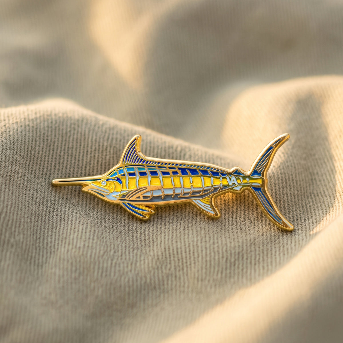 Blue Marlin pin resting on tan fabric