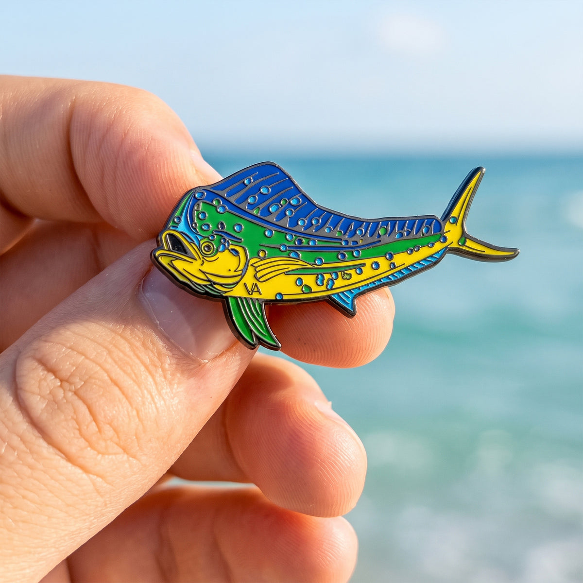 Mahi Mahi pin held in hand with sky and ocean in the background