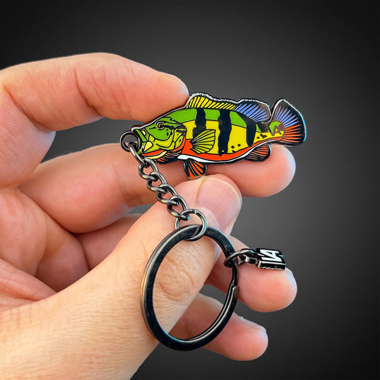 Peacock Bass keychain held in hand against a dark background