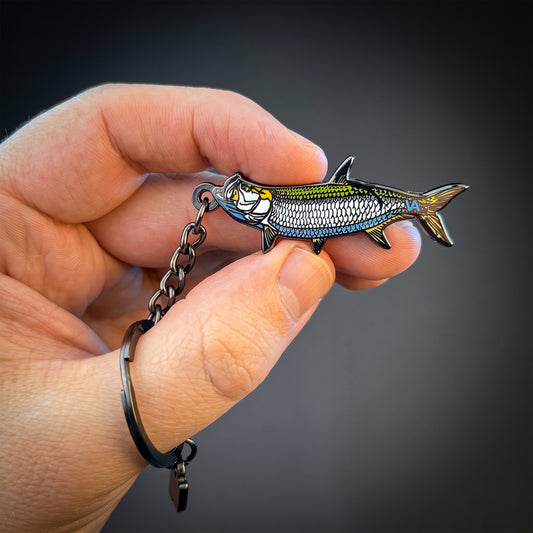 Tarpon keychain held in hand against a dark background