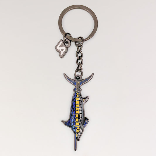Blue Marlin keychain, black nickel hard enamel charm with the VEDUTA DESIGN VA logo charm and chain, on a light studio background