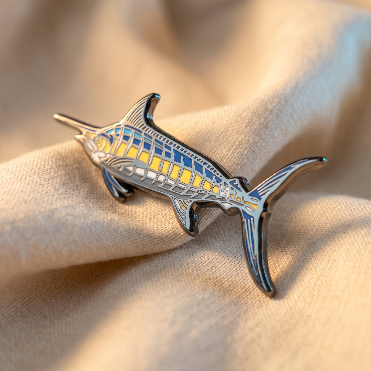 Blue Marlin pin resting on tan fabric