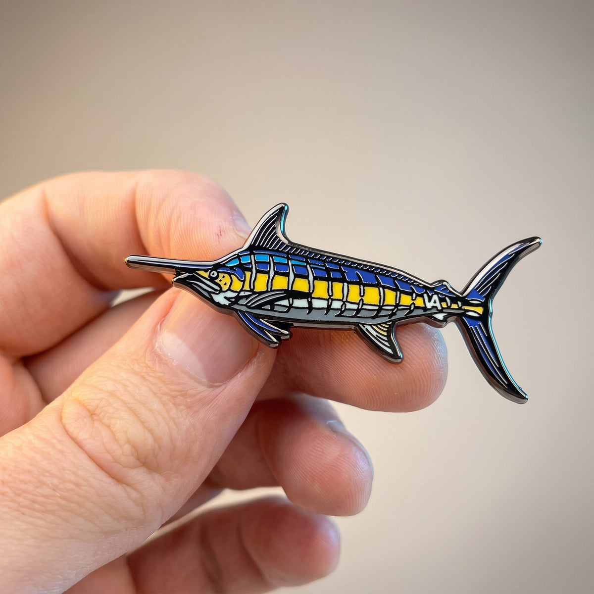 Blue Marlin pin held in hand, warm background