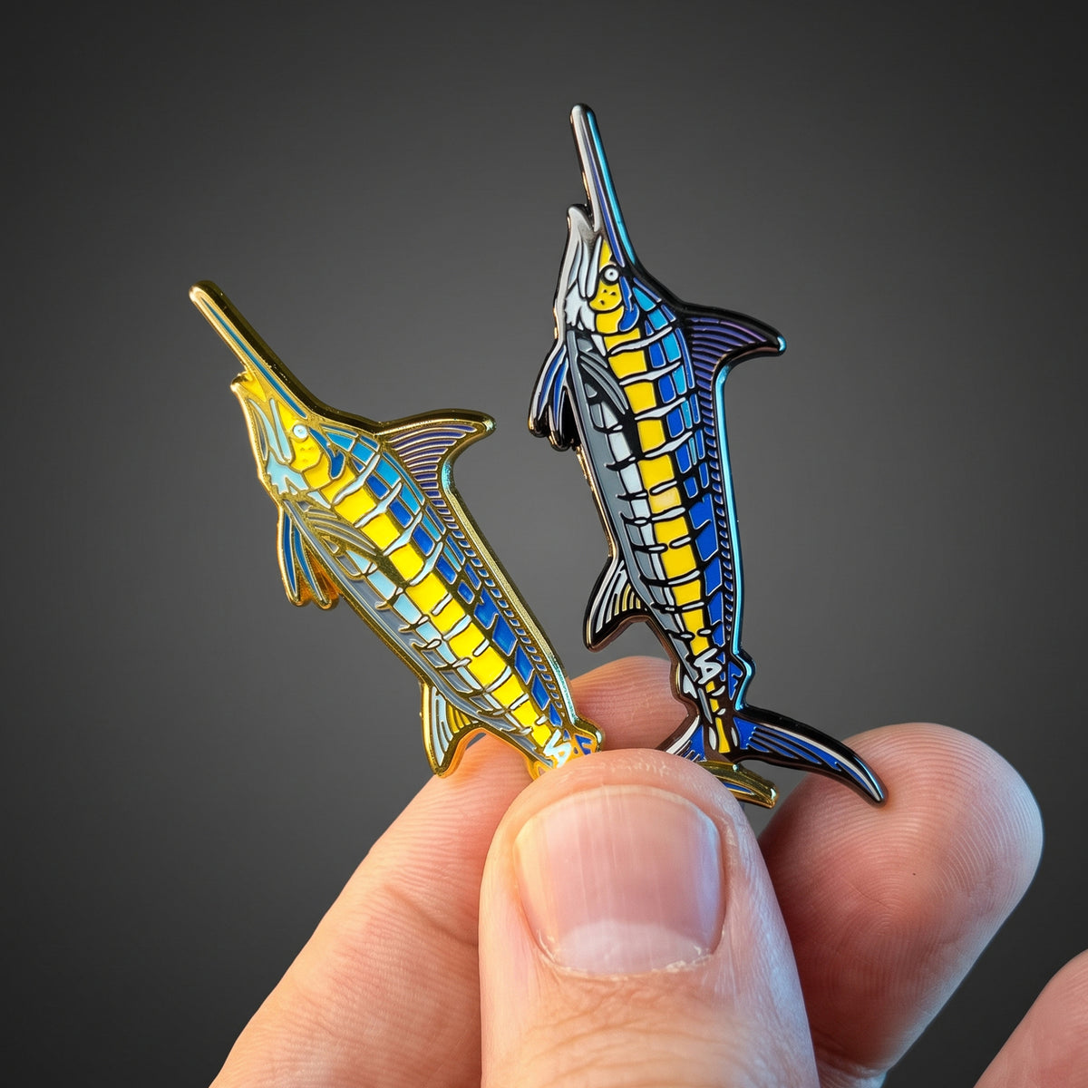 Gold and black nickel Blue Marlin pins held together, side by side