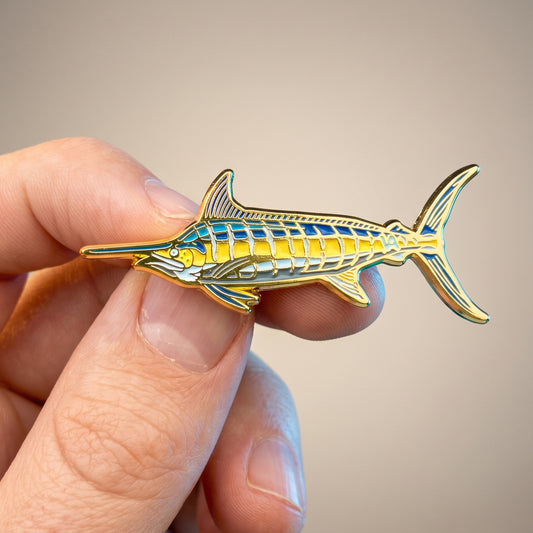 Blue Marlin pin held in hand, warm background