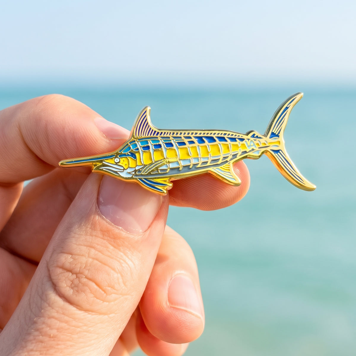 Blue Marlin pin held in hand with ocean and sky in the background
