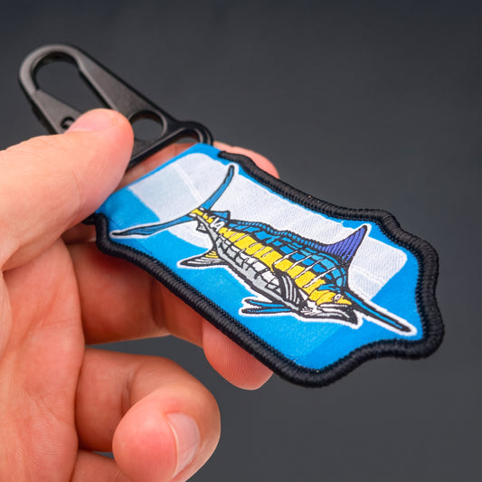 Blue Marlin woven keychain held in hand against a dark background