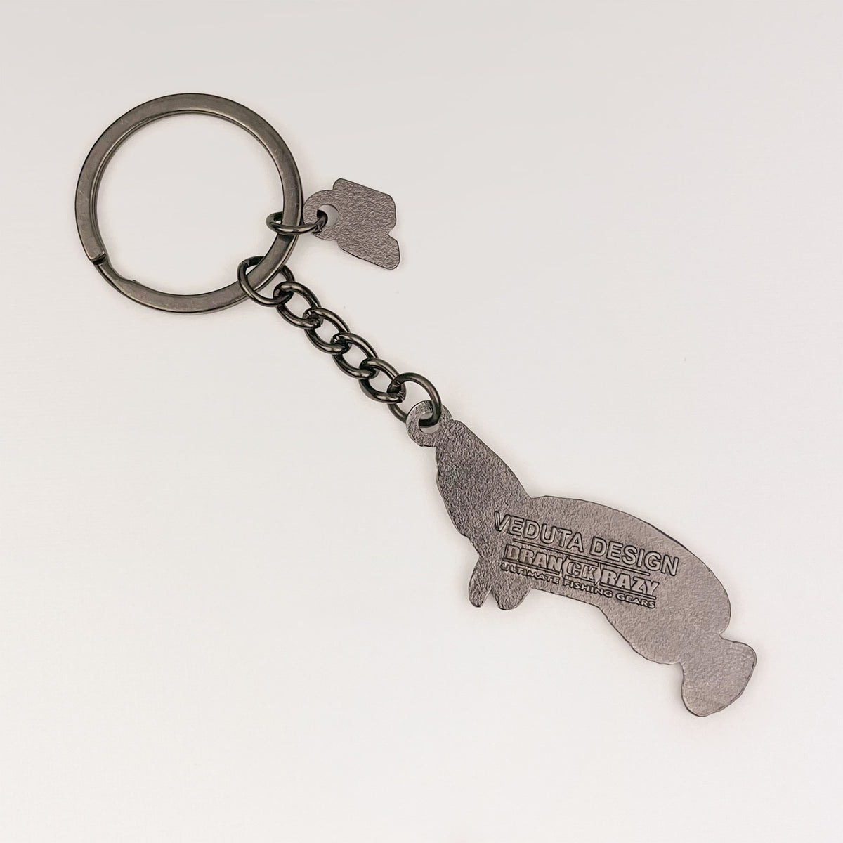 Back of the Giant Snakehead keychain charm with embossed VEDUTA DESIGN x DRANCKRAZY logo