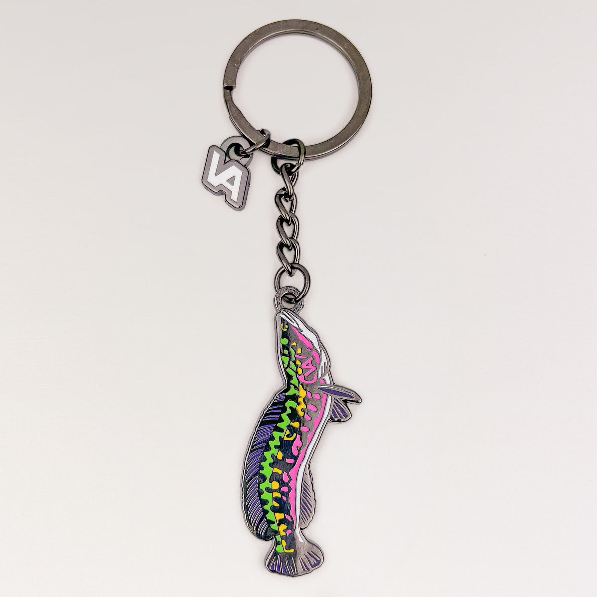 Giant Snakehead keychain, black nickel hard enamel charm with the VEDUTA DESIGN VA logo charm and chain, on a light studio background