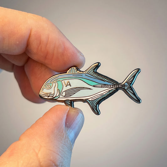 Close-up of Giant Trevally hard enamel pin held in hand