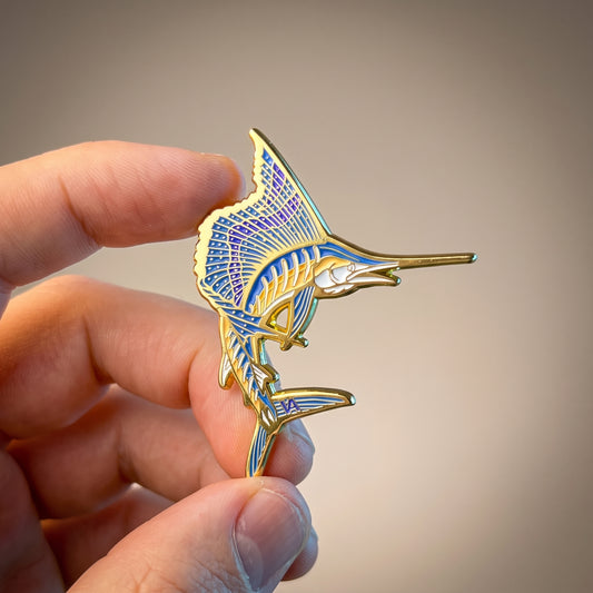 Sailfish pin in gold enamel, held in hand close-up