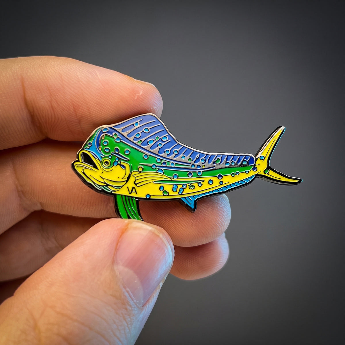 Mahi Mahi pin held in hand against a dark background