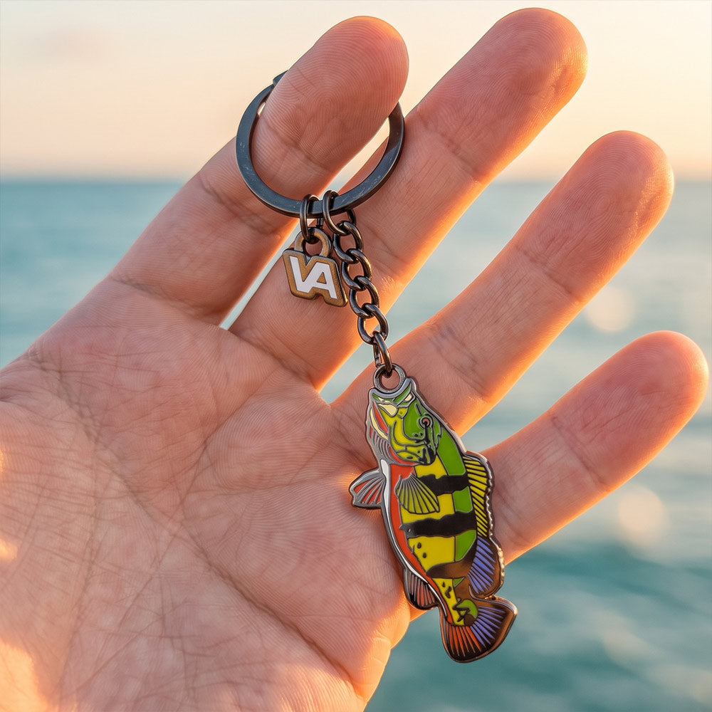 Peacock Bass keychain held in hand with the ocean in the background