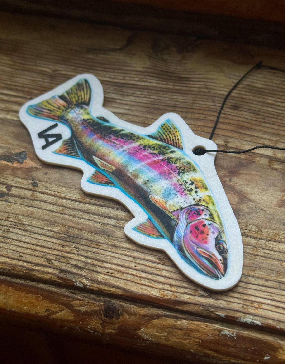 Rainbow Trout air freshener with cord on a wooden surface