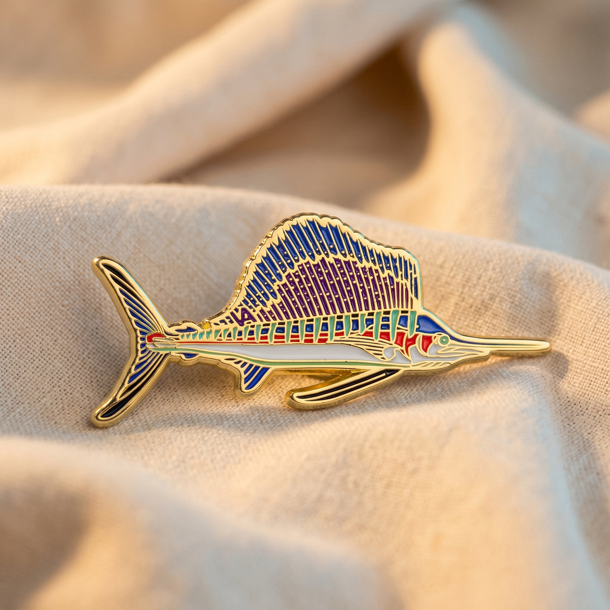 Sailfish pin resting on draped tan fabric