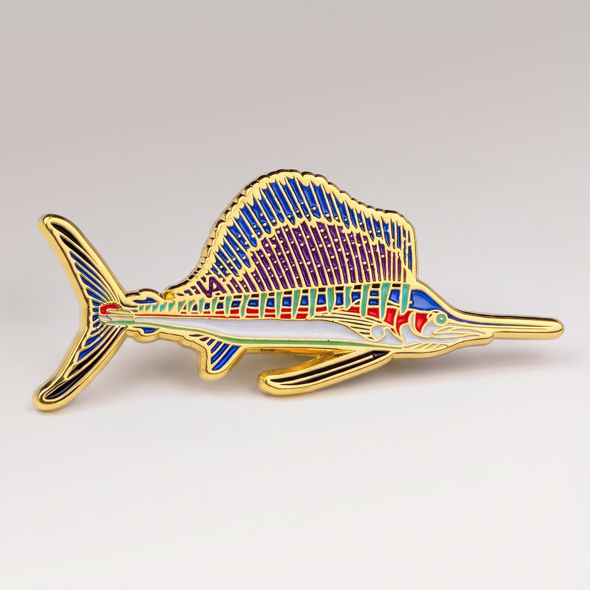 Gold and purple enamel Sailfish pin, profile design, on a white studio background
