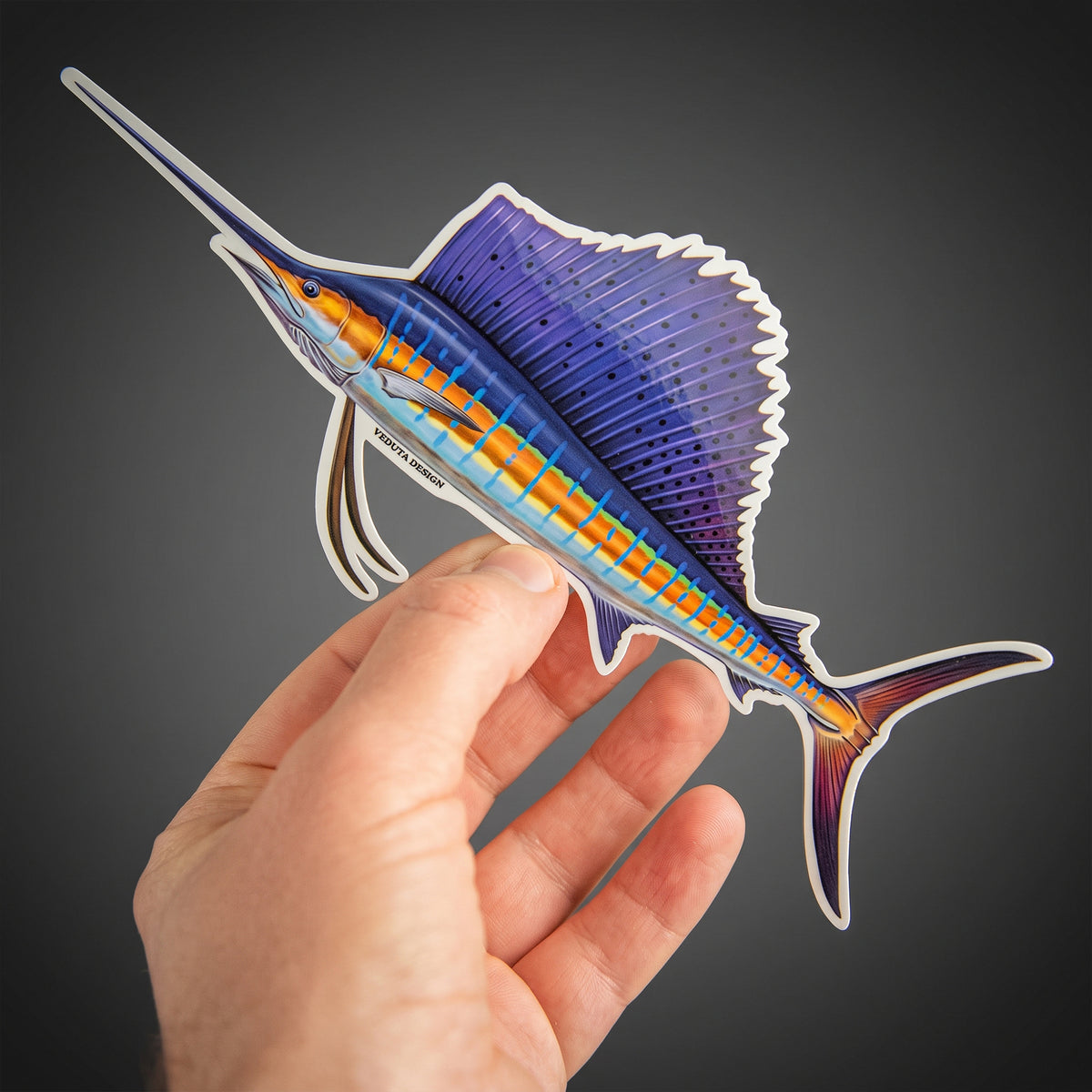 Sailfish sticker held in hand against a dark background