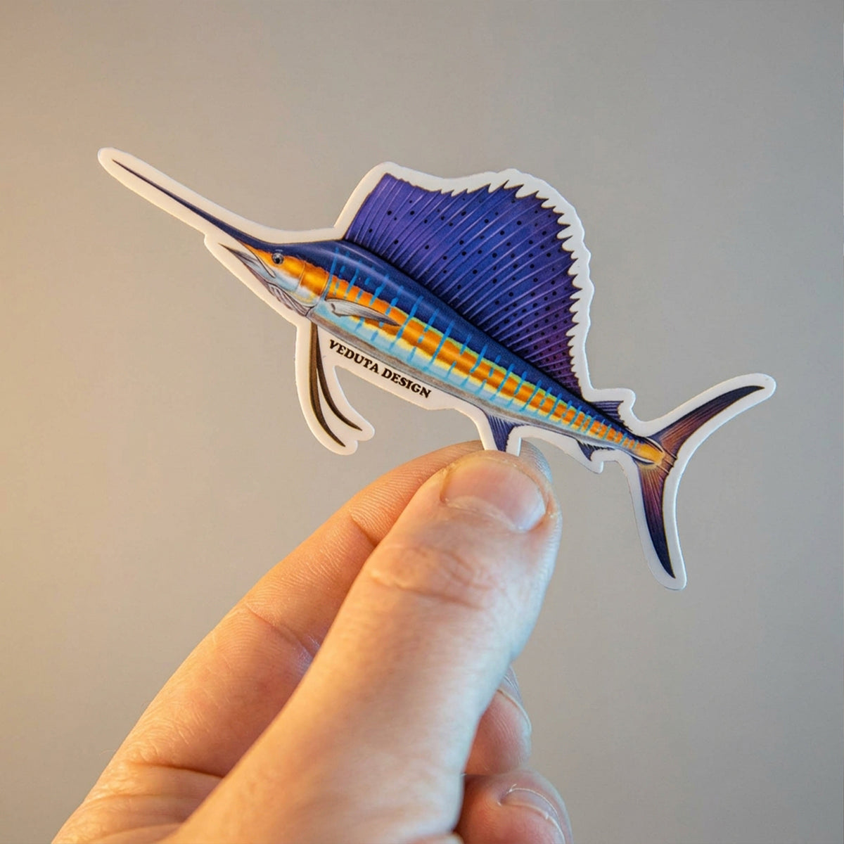 Sailfish sticker held in hand against a plain background