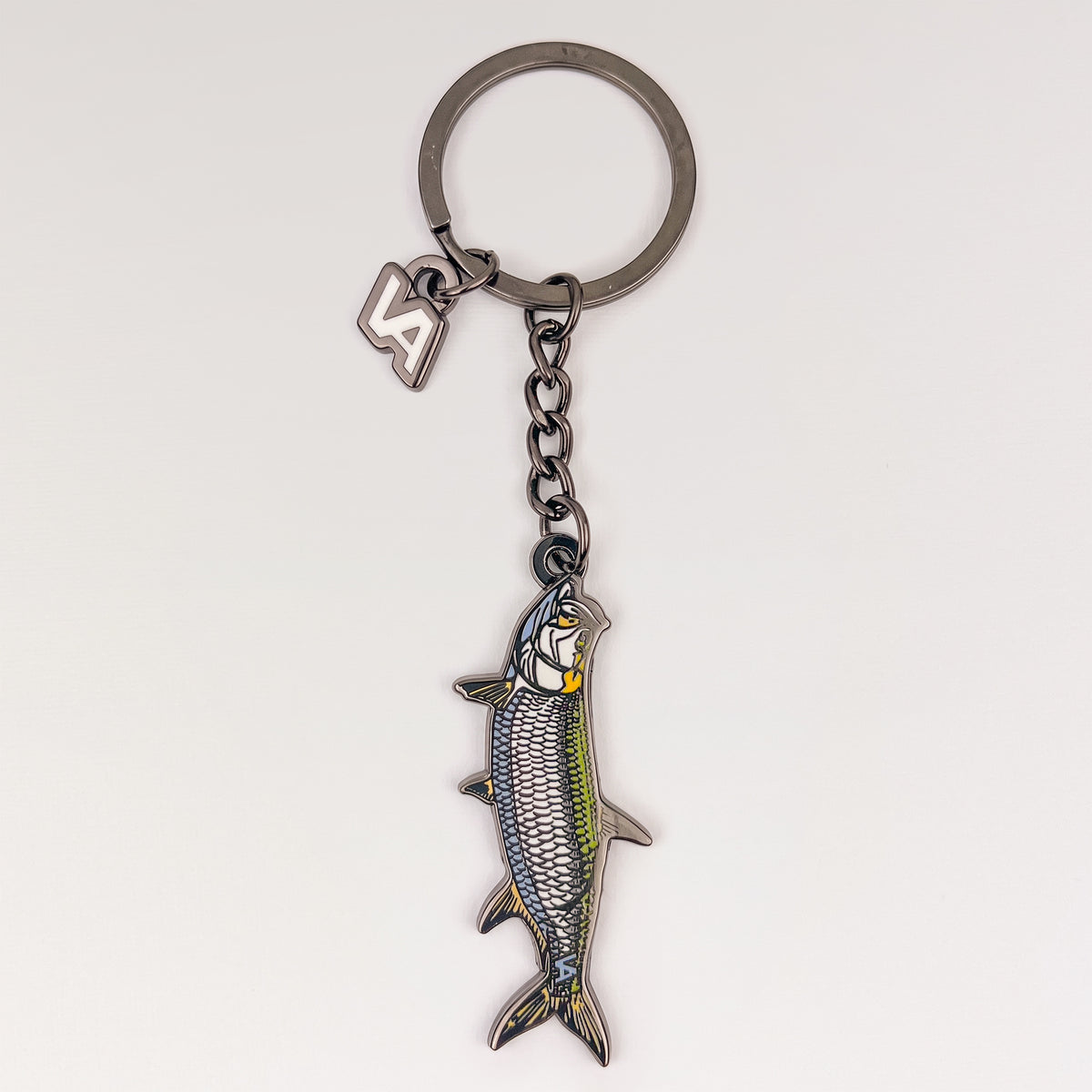 Tarpon keychain, black nickel hard enamel charm with the VEDUTA DESIGN VA logo charm and chain, on a light studio background