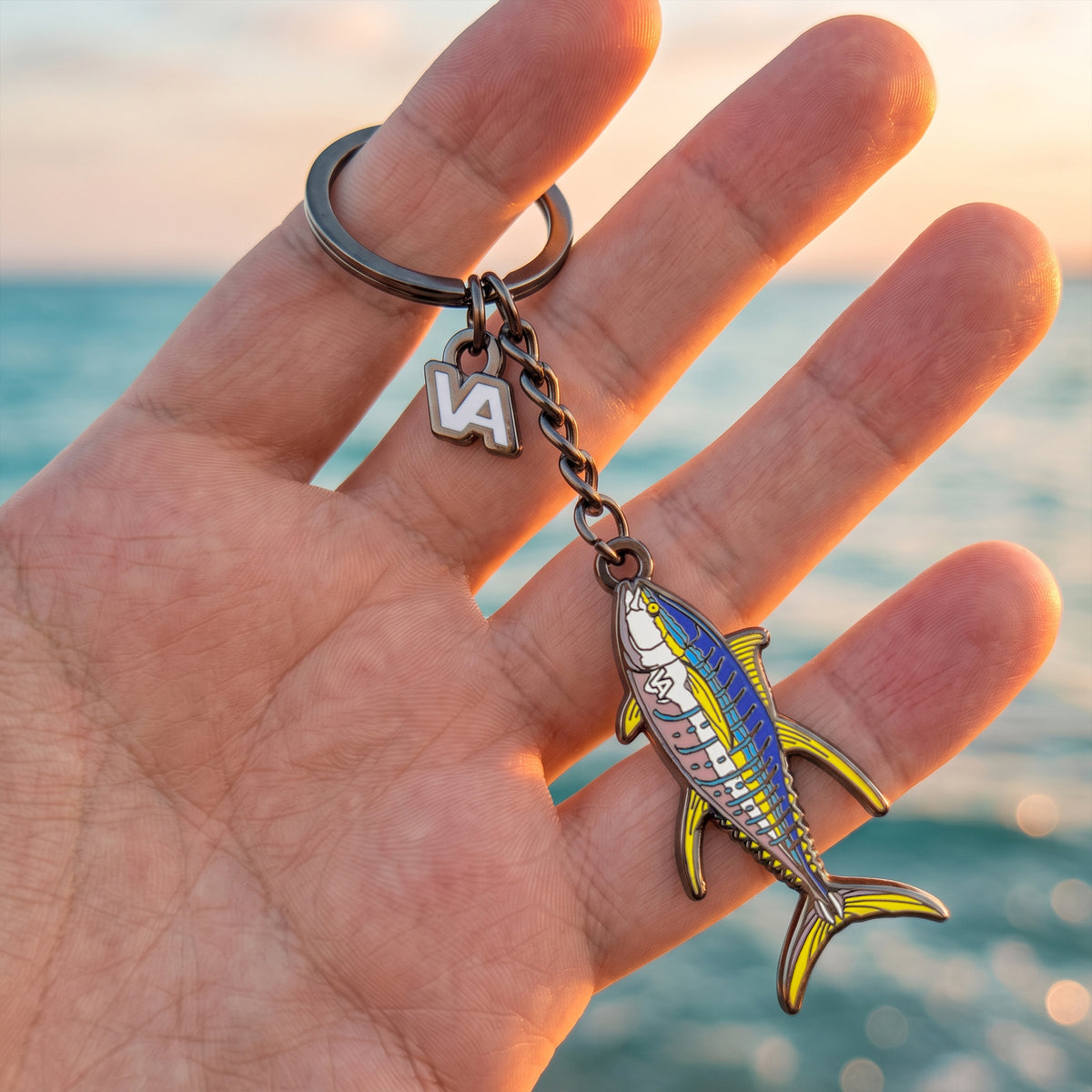 Yellowfin Tuna keychain held in hand with the ocean at sunset in the background