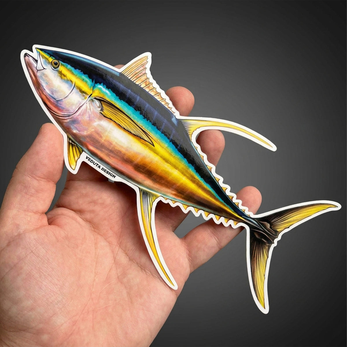 Yellowfin Tuna sticker held in hand against a dark background